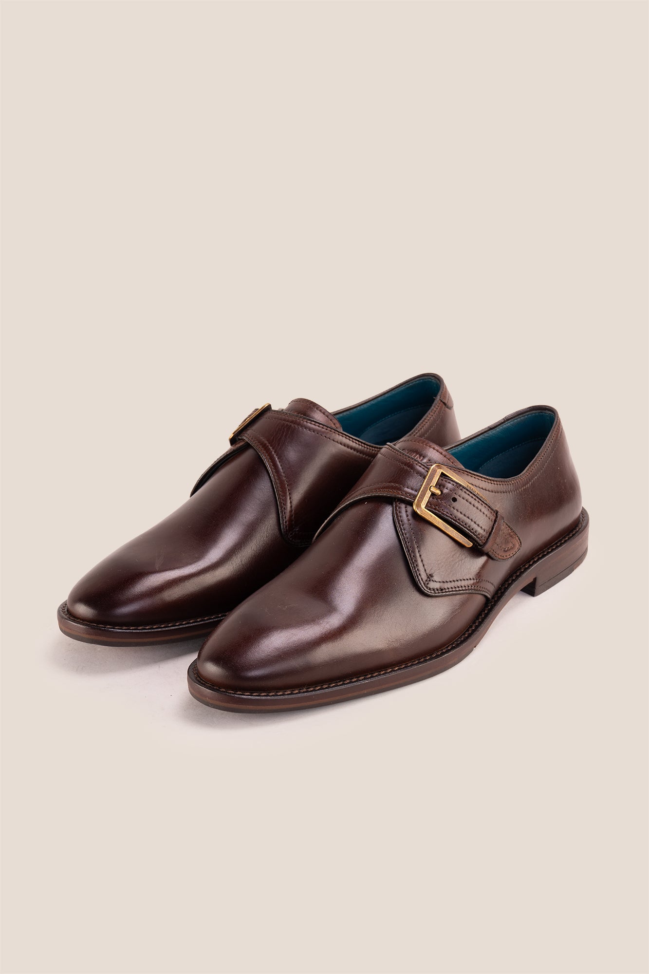 Premium men's brown leather single monk strap dress shoes by Oswin Hyde London featuring a plain toe, adjustable golden buckle, contrast sole stitching, and a cushioned teal interior.