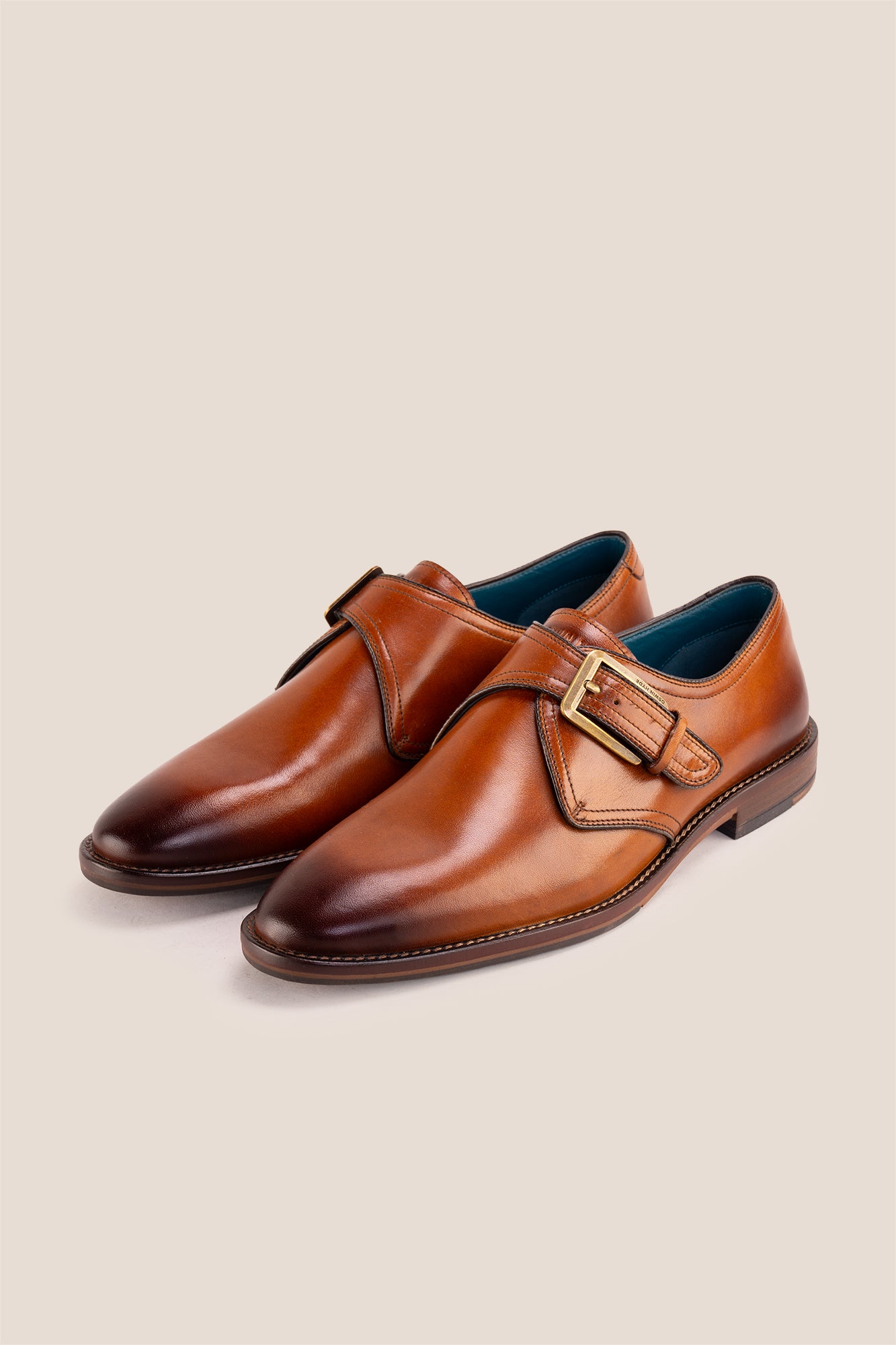 Premium men's tan leather single monk strap dress shoes by Oswin Hyde London featuring a plain toe, adjustable golden buckle, contrast sole stitching, and a cushioned teal interior.