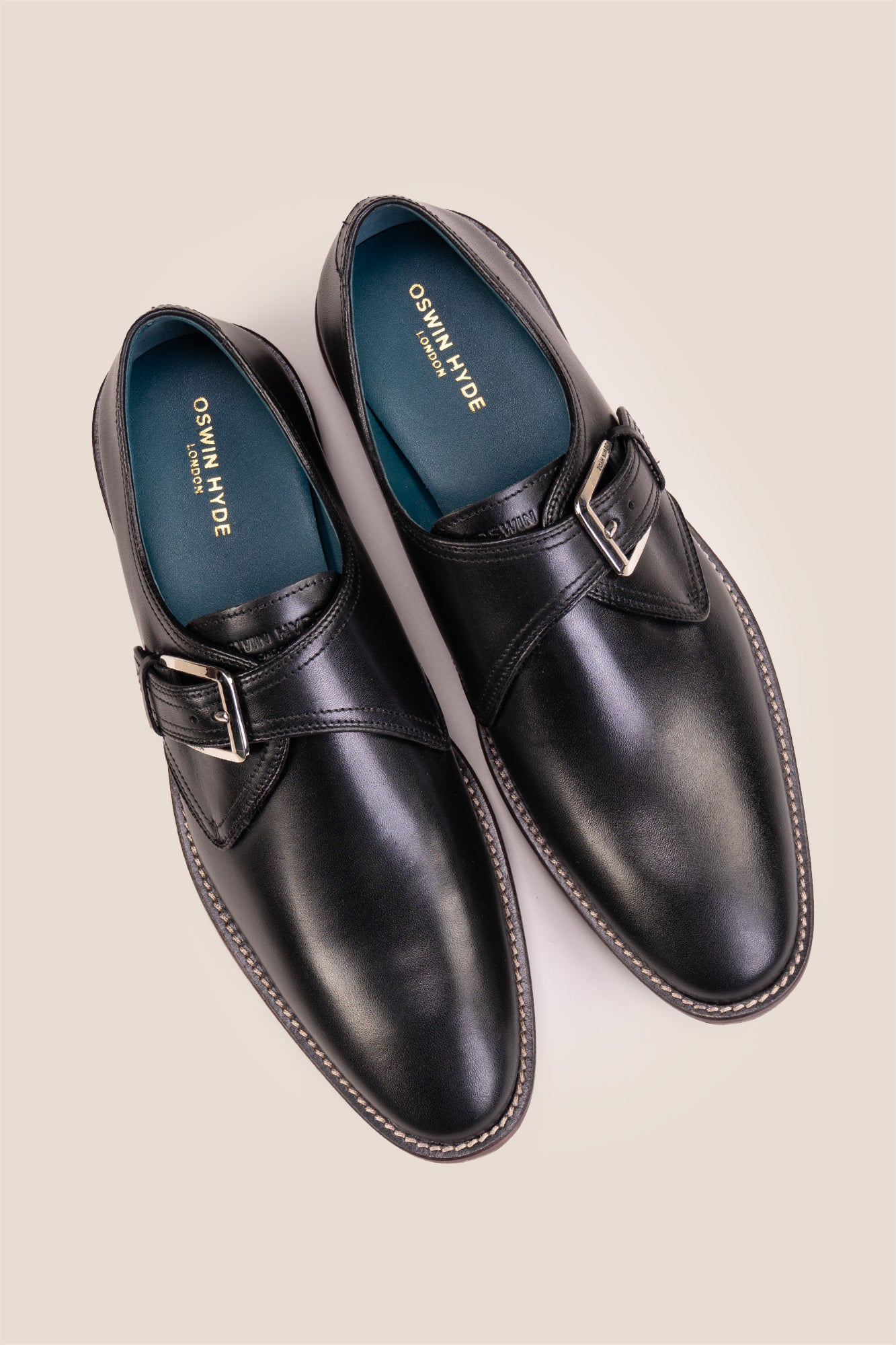 Premium men's black leather single monk strap dress shoes by Oswin Hyde London featuring a plain toe, adjustable silver buckle, contrast sole stitching, and a cushioned teal interior.
