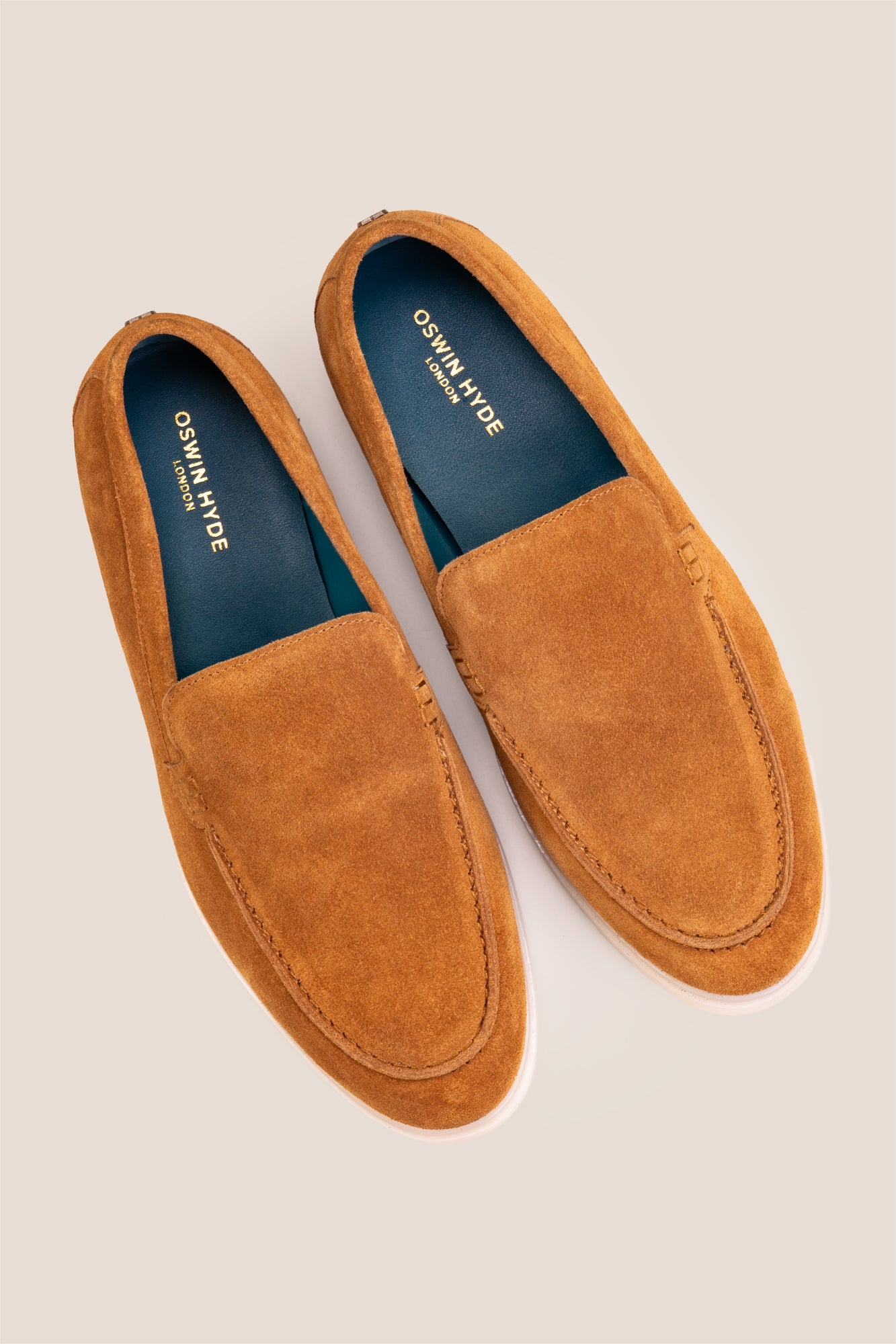 Top-down view of Oswin Hyde Morgan tobacco suede loafers, highlighting the teal blue inner lining and gold logo branding.