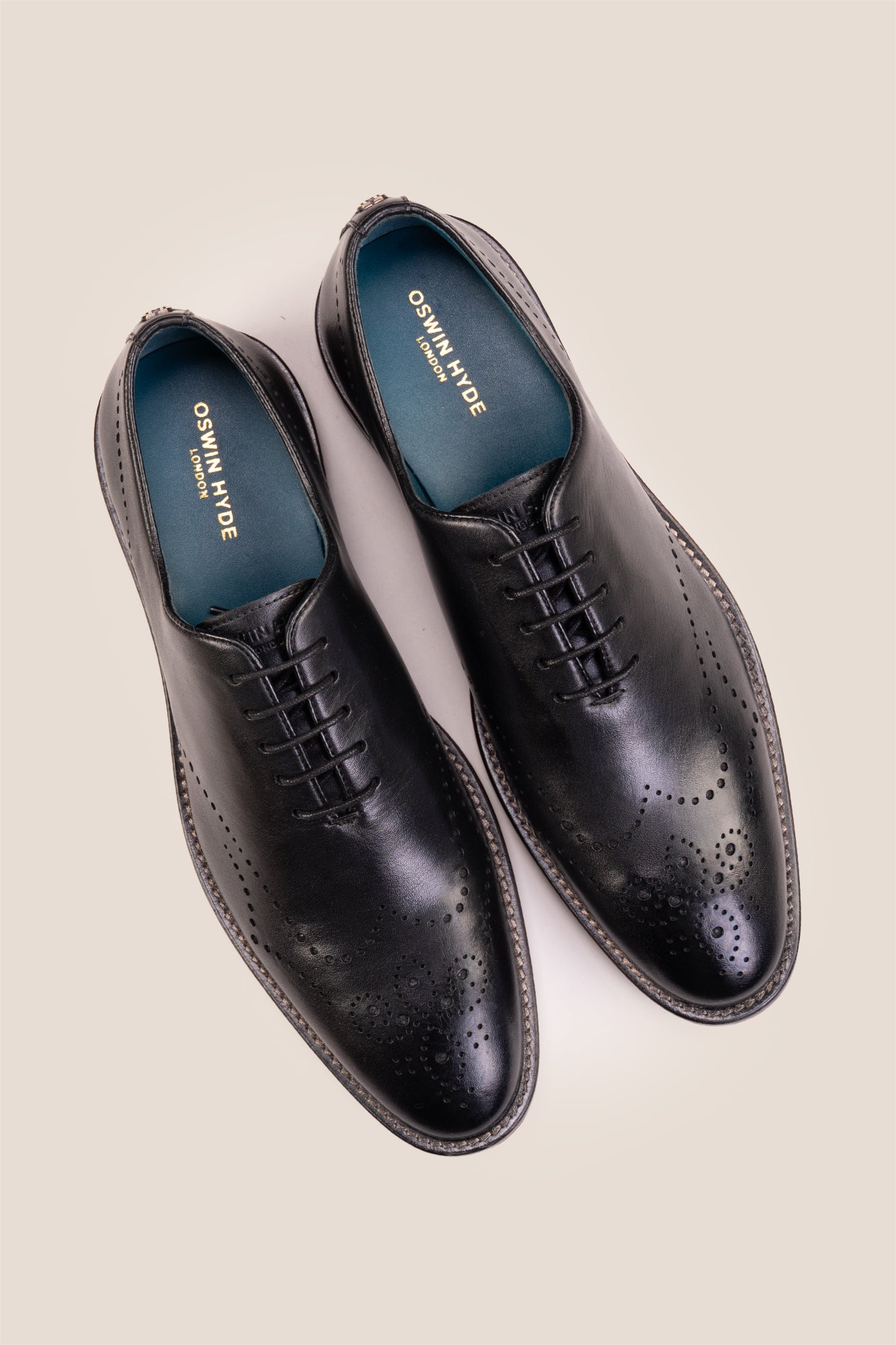 Oswin Hyde London premium black leather wingtip brogues with a toe medallion pattern, contrast welt stitching, and a cushioned teal interior.