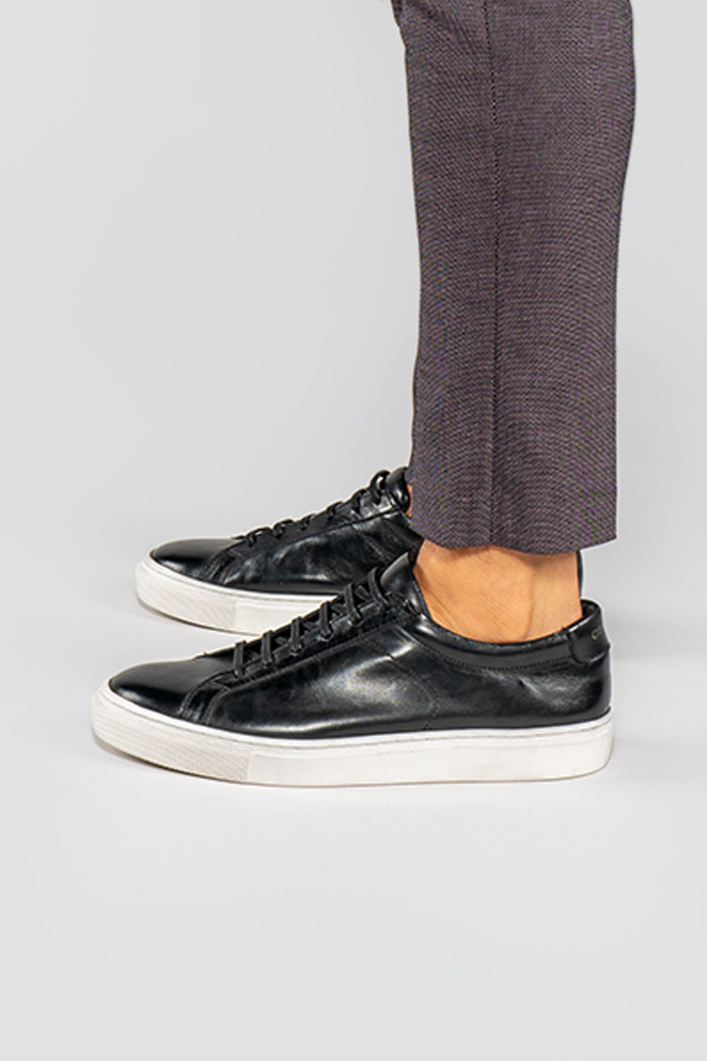 model wearing Men's black leather trainers with white sole