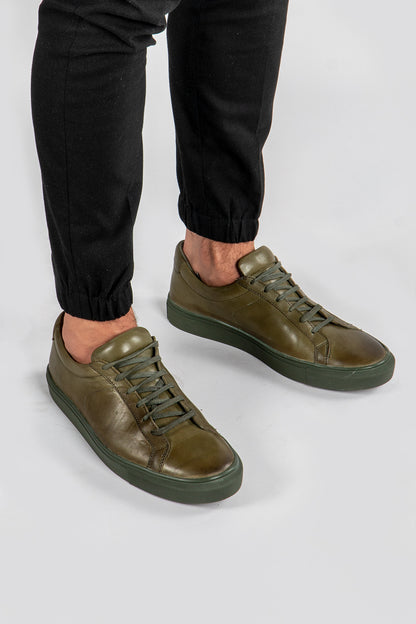 model wearing Men's green leather trainers with green sole